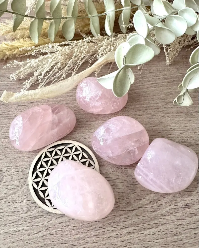 Quartz rose pierre naturelle en pierres roulées polies, présentées sur décor bois et végétal