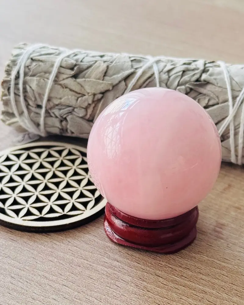 Sphère en quartz rose, pierre naturelle polie présentée sur un support