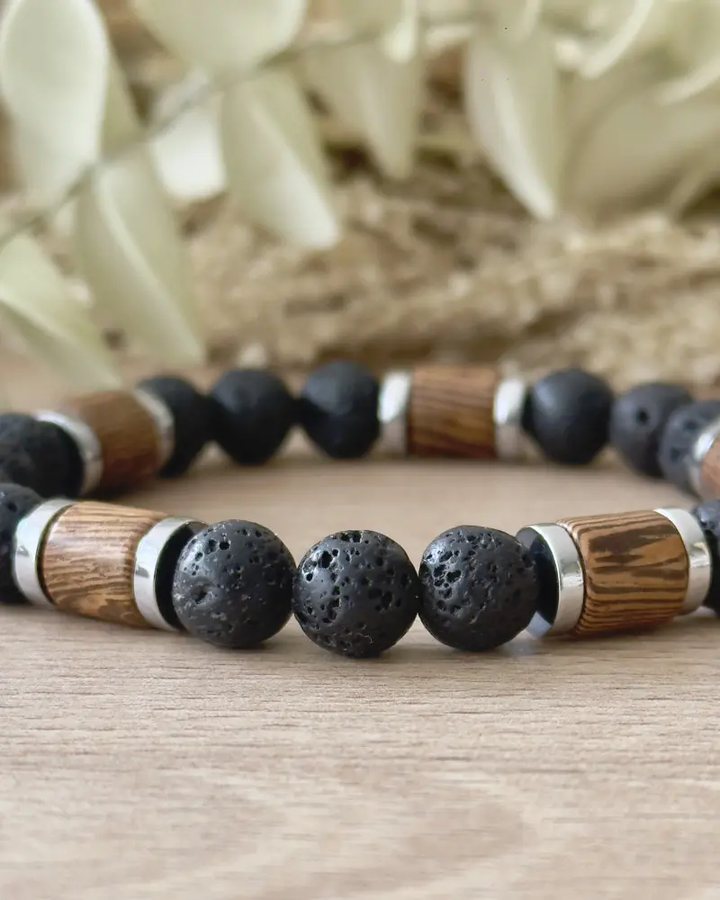Gros plan sur les perles en pierre de lave naturelle, les éléments en bois et les séparateurs en acier inoxydable du bracelet homme Bois & Pierre.
